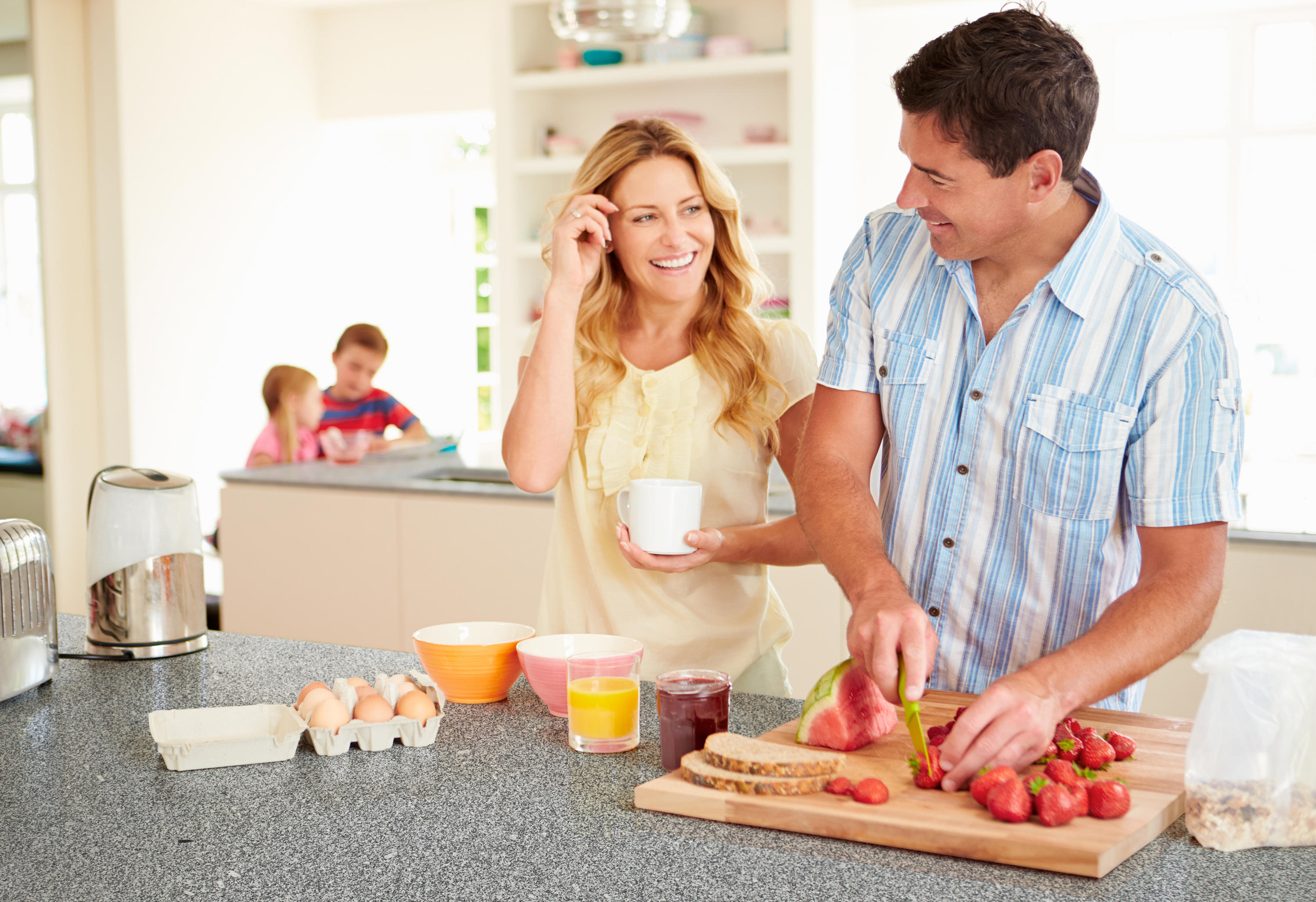 Муж помогает вставлять жене. Семья на кухне. Мужчина и женщина завтракают. Счастливая семья на кухне. Семья кухня обед.