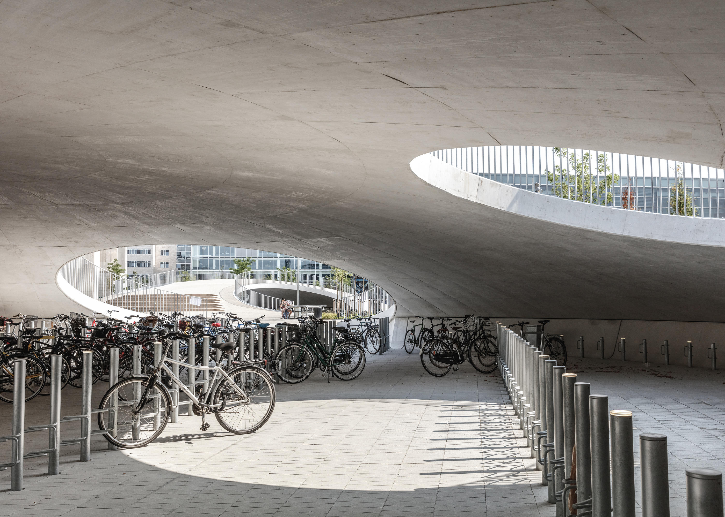 Bicycle parking under the hills by COBE Industrial buildings