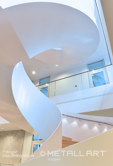 Impressively rounded stringer stairs with LED lighting at Norderstedt Bank | Sistemas de escalera | MetallArt Treppen