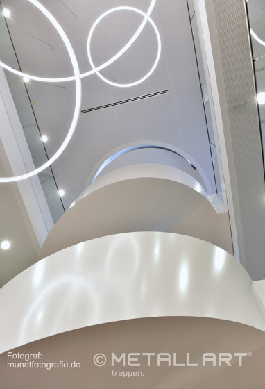 Eindrucksvoll gerundete Wangentreppe mit LED-Handlaufbeleuchtung in der Norderstedter Bank | Treppensysteme | MetallArt Treppen