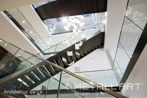 Stylish steel stairs featuring all-glass railings at WMD in Ahrensburg | Stair railings | MetallArt Treppen