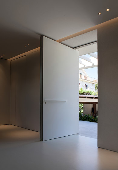 Synua | La porte blindée pour les grandes dimensions, avec fonctionnement
pivotant vertical et coplanaire au mur. | Portes d'entrée | Oikos – Architetture d’ingresso