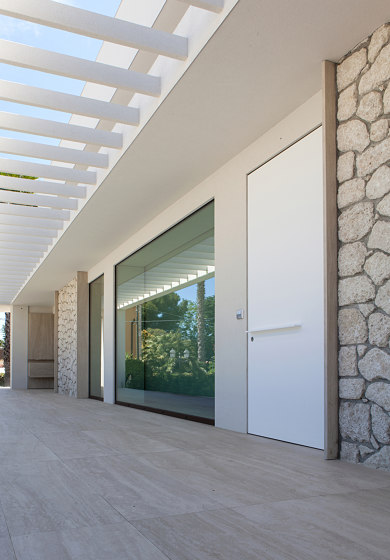 Synua | La porte blindée pour les grandes dimensions, avec fonctionnement
pivotant vertical et coplanaire au mur. | Portes d'entrée | Oikos – Architetture d’ingresso