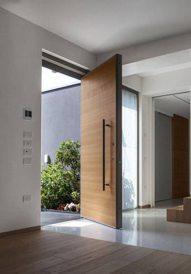 Synua | The safety door for large dimensions, with vertical pivot operation and installation coplanar with the wall. by Oikos – Architetture d’ingresso | Entrance doors