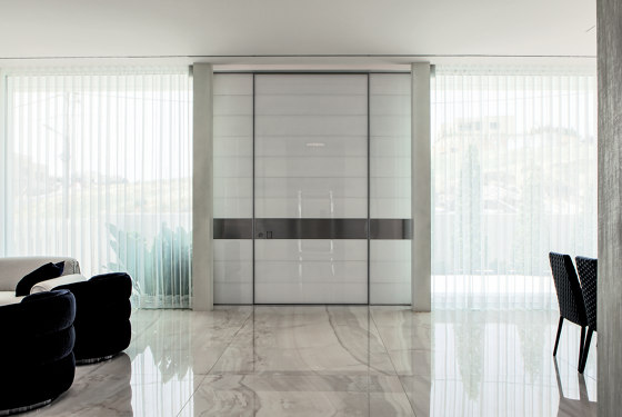 Synua | The safety door for large dimensions, with vertical pivot operation and installation coplanar with the wall. | Front doors | Oikos – Architetture d’ingresso